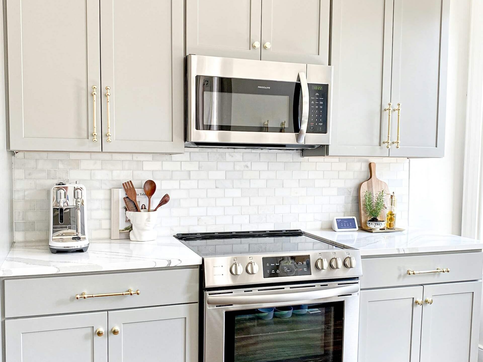 Kök med grå köksskåp och mässingsbeslag.