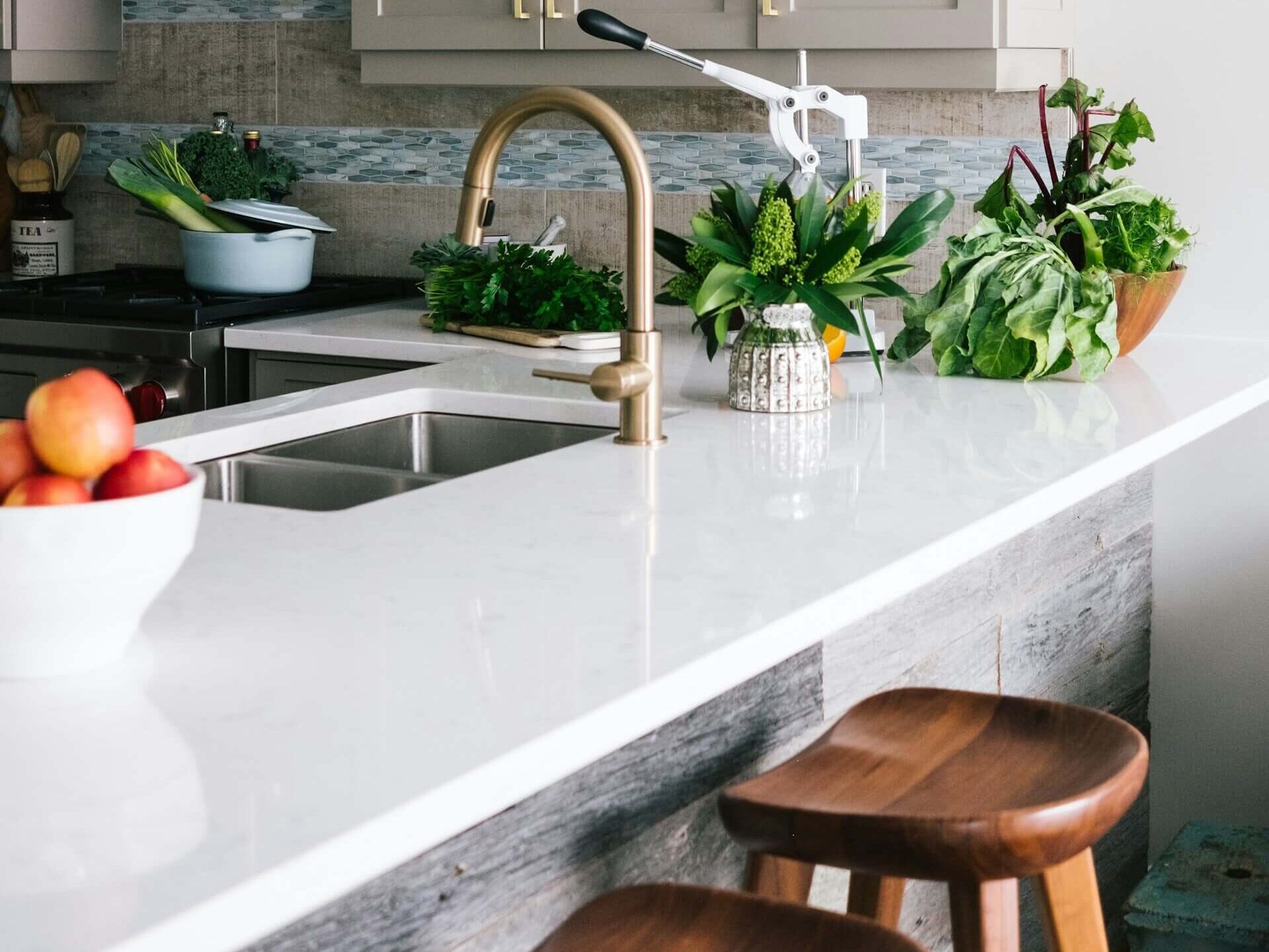 Närbild på vit bänkskiva i kök med blandare i mässing.